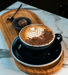 Delicious mocha coffee with heart shaped latte art and chocolate shavings. Served on a wooden tray with truffle and spoon. Ideal for cafes, coffee brands, dessert promotions, and food blogs.