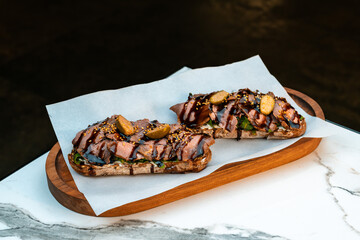 Gourmet bruschetta with pastrami, cream cheese, arugula, capers, and balsamic glaze on multigrain...