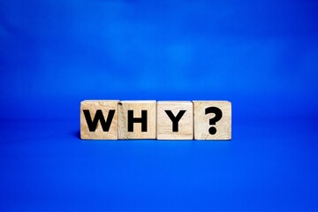 wooden cubes with the word WHY? on a blue background.