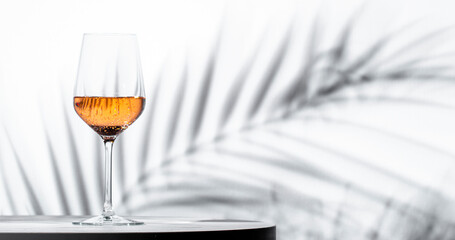 refreshing glass of rose pink wine at a stylish bar with elegant palm leaves in the background