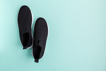 Pair of black sneakers on a blue background.