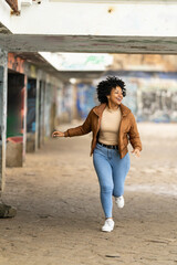 Young woman running under a bridge near the sea enjoying a break from routine