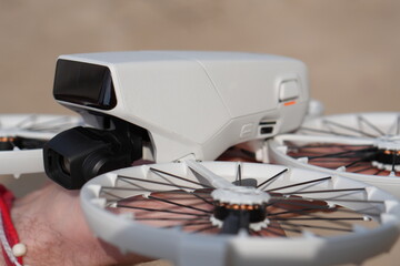 Close-Up View of the Body and Propeller Guards of a White FPV Drone, Showing the Camera and Sensors