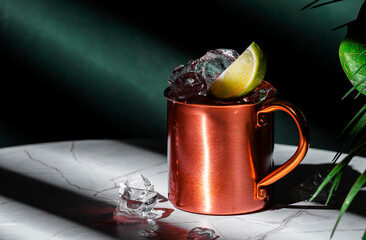 London mule alcoholic cocktail drink with gin, lime juice and ice. Green background, hard light