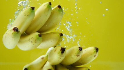 Bunch of mini bananas submerged in water with many bubbles, slow motion. - Powered by Adobe