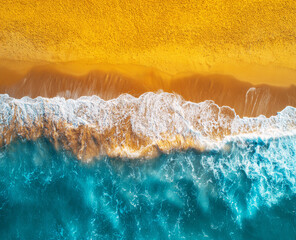 Aerial view of the beach with waves and sand. Bright ocean beach and water.