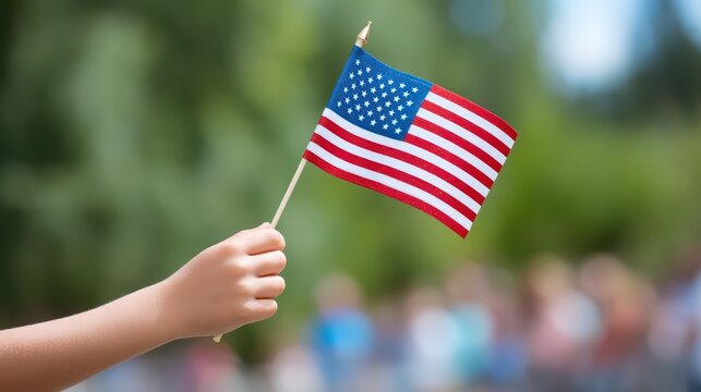 Hand Holding Small American Flag in Celebration of National Pride and Patriotism Outdoor Event with Blurred Background