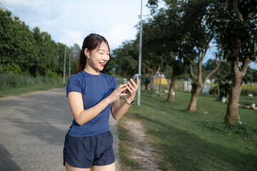 A woman is walking down a road while looking at her cell phone
