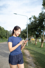 A woman is walking down a road with her phone in her hand
