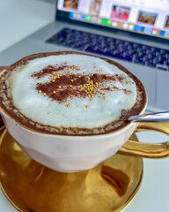 Close-up of a beautifully crafted cappuccino in a golden cup, topped with cocoa powder and...