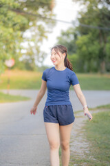 A woman in a blue shirt and blue shorts walks down a road