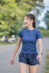 A woman is walking down a street wearing a blue shirt and shorts