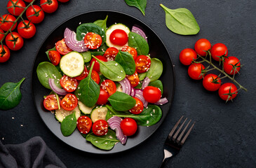 Healthy salad with spinach, tomatoes, cucumber, onion, sesame and olive oil, top view