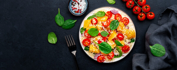 vegan salad with couscous, cherry tomatoes, red onion, fresh baby spinach and juicy orange, top view