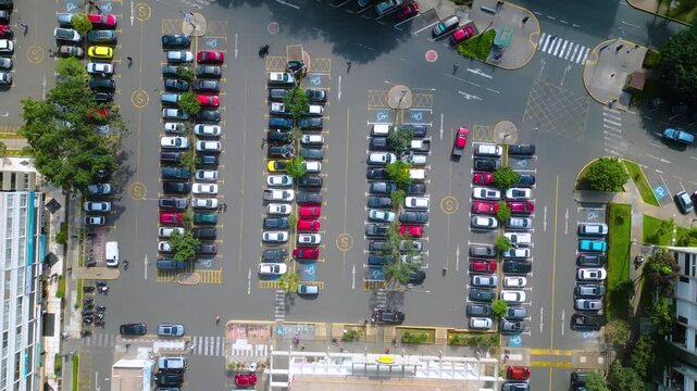 Vista cenital con dron de un estacionamiento de coches en actividad durante el d&iacute;a.