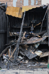 Vertical view of a burnt structure with scorched beams, collapsed boards, and visible fire damage.