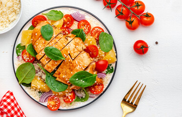 Salad with chicken fillet, couscous, cherry tomatoes, red onion, fresh spinach and orange slices, top view