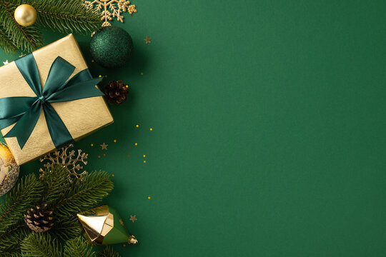 Golden present wrapped with green bow surrounded by festive decorations and green pine
