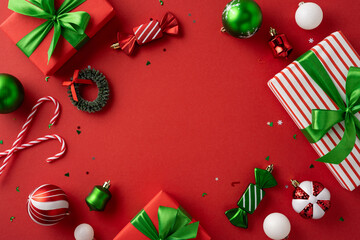 Festive red background featuring green and white tones of Christmas ornaments and gifts. Ideal for...