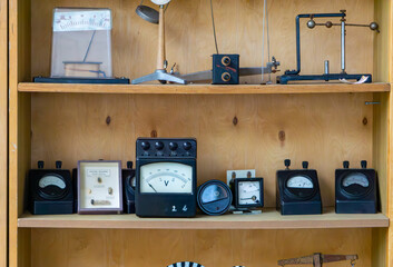 Set of vintage analog meters and physics instruments on a wooden shelf. Old voltmeters, ammeters,...