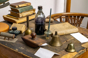 Vintage teacher’s desk with old books, inkwells, school bells, and classroom accessories. Styled...