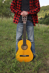 young guy in a red shirt with an acoustic guitar in nature