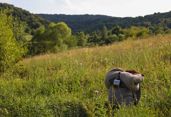 grey hiking backpack with folded blanket and tin mugs outdoors with green mountains in background