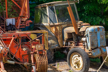 Damaged communist-era tractor and old agricultural machine at a scrapyard. Rusty farm equipment...