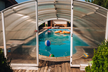 Photo of a large covered swimming pool in a hotel with blue water and inflatable accessories,...