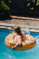 An adult man swims on an inflatable ring in a pool in summer during his leisure time on a weekend.