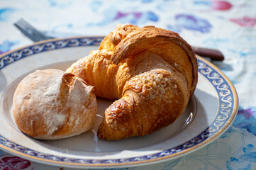 Italian breakfast, fresh baked butter croissant with sugar, served outdoor in sunny day