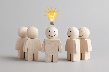 A team of wooden figures stands together, one with a bright lightbulb above, symbolizing a great idea