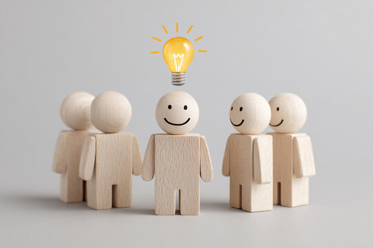 A team of wooden figures stands together, one with a bright lightbulb above, symbolizing a great idea