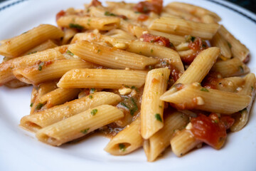 Italian everyday food, cooked pasta penne with tomatoes sauce, garlic and parsley