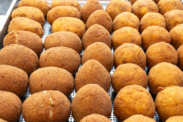 Arancini Sicilian, deep-fried rice balls made with risotto, filled with ingredients mozzarella, ragu, peas, coated in breadcrumbs fried to crispy, brown on market in Palermo, Sicily