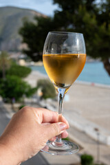 Celebration, birthday party, hand with glass of sweet muscat white wine from Pantelleria island on holiday on Mondello beach, Palermo, Sicily, Italy