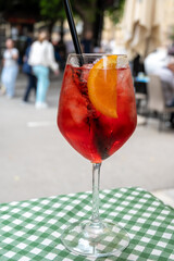 Spritz Campari red bitter long drink cocktail maid with liqueur, prosecco sparkling wine, ice cubes and piece of orange, street view of Palermo, Italy