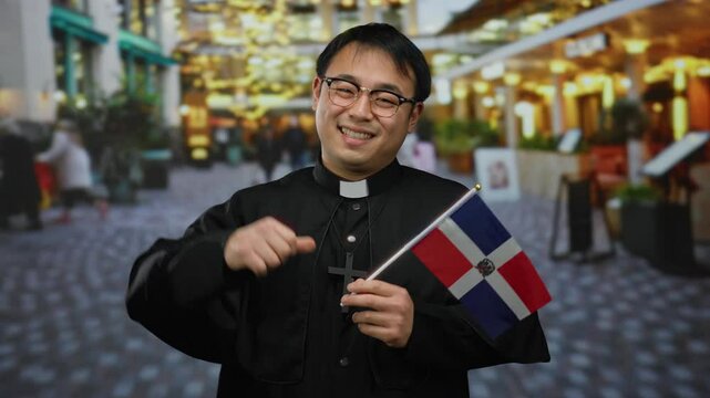Priest holding dominican flag smiling in urban street setting with blurred lights and architecture background