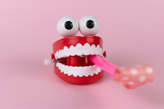 Funny Wind-Up Chattering Teeth Toy with Googly Eyes on Pink Background