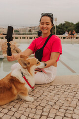 Young girl with Corgi recording video on phone share via app her travel vacation. Gen Z influencer...