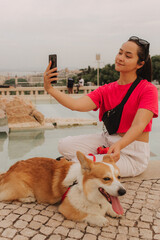 Young girl with Corgi recording video on phone share via app her travel vacation. Gen Z influencer...