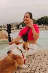 Young girl with Corgi recording video on phone share via app her travel vacation. Gen Z influencer...
