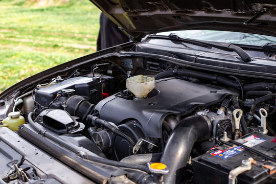 Car engine with open hood, engine components and funnel for filling engine oil