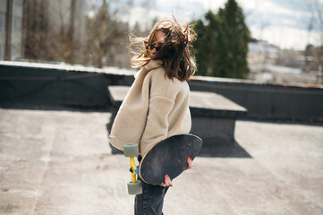 Young Adult with Skateboard on Windy Rooftop