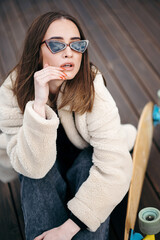 Fashionable Woman with Longboard on Wooden Deck