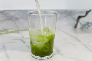 Matcha latte, making a matcha latte with ice, milk, bamboo whisk green tea. 