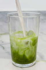 Matcha latte, making a matcha latte with ice, milk, bamboo whisk green tea. 