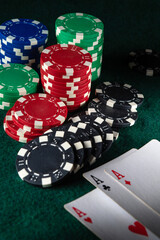 Stacks of vibrant poker chips in various colors are arranged alongside three aces on a deep green felt surface, highlighting an exciting moment of a game night with friends