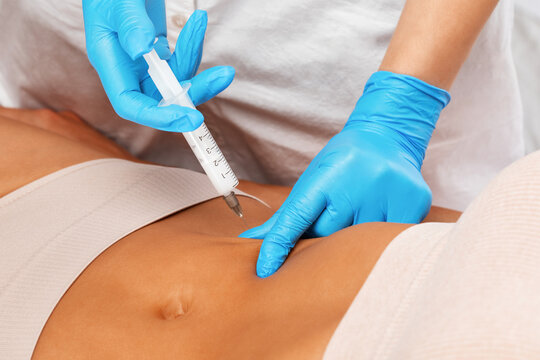 Aesthetic cosmetologist makes lipolytic injections to burn fat on the body of a woman. Female aesthetic cosmetology in a beauty salon.Cosmetology concept.