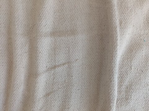 Manta de cama bege/marrom desnaturado com dobras e amassados visto de perto. Textura de colcha de cama